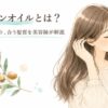 「モロッカンオイルとは？効果とデメリット、合う髪質を美容師が解説」という見出しが書かれた画像です。目を閉じて艶やかなロングヘアに触れながら微笑む女性が、手にはモロッカンオイルのボトルを持っています。左側には成分を思わせるアルガンの実と葉のイラストが水彩画タッチで美しく添えられています。