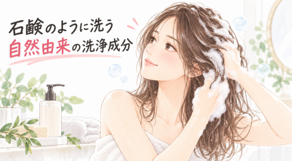 「石鹸のように洗う 自然由来の洗浄成分」について解説した図解。植物が飾られた清潔感のある浴室で、豊かな泡を使って気持ちよさそうに髪を洗う女性のイラストとともに、自然由来の石鹸系洗浄成分の特徴や魅力を分かりやすく表現しています。