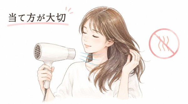 「当て方が大切」という見出しの図解画像です。白いドライヤーでやさしく髪を乾かす笑顔の女性のイラストが描かれています。ドライヤーからは青い風が出ており、右側には熱を意味する赤い波線に禁止マークが重ねられています。熱を当てすぎず、正しい風の当て方で髪をケアする重要性を伝えています。